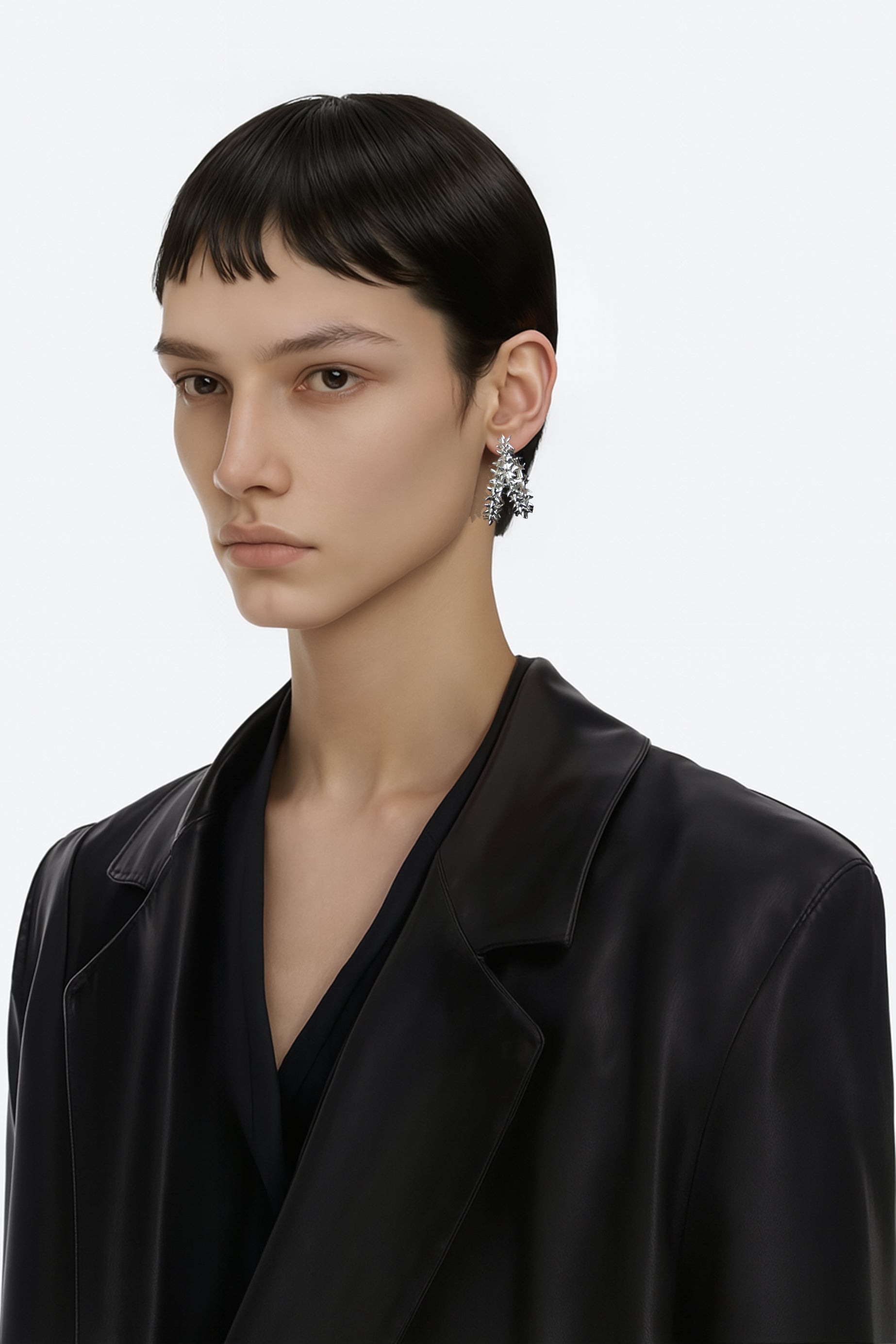 A brass silver spikes hoop fantasy earring worn by an AI model with leather black tailored jacket and short dark hair view from 3/4