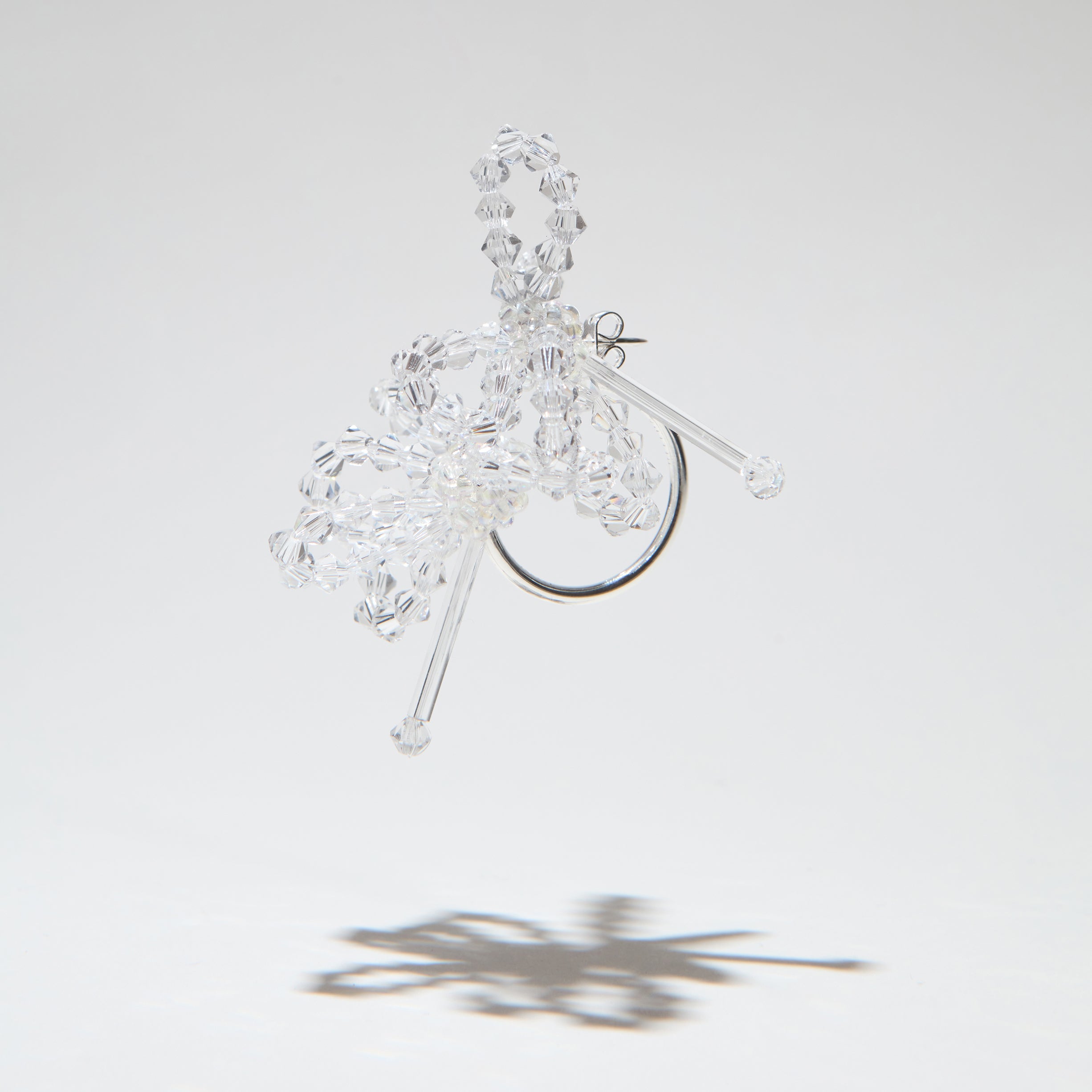 A clear crystal and glass earrings with a half loop closure, displayed against a white background.