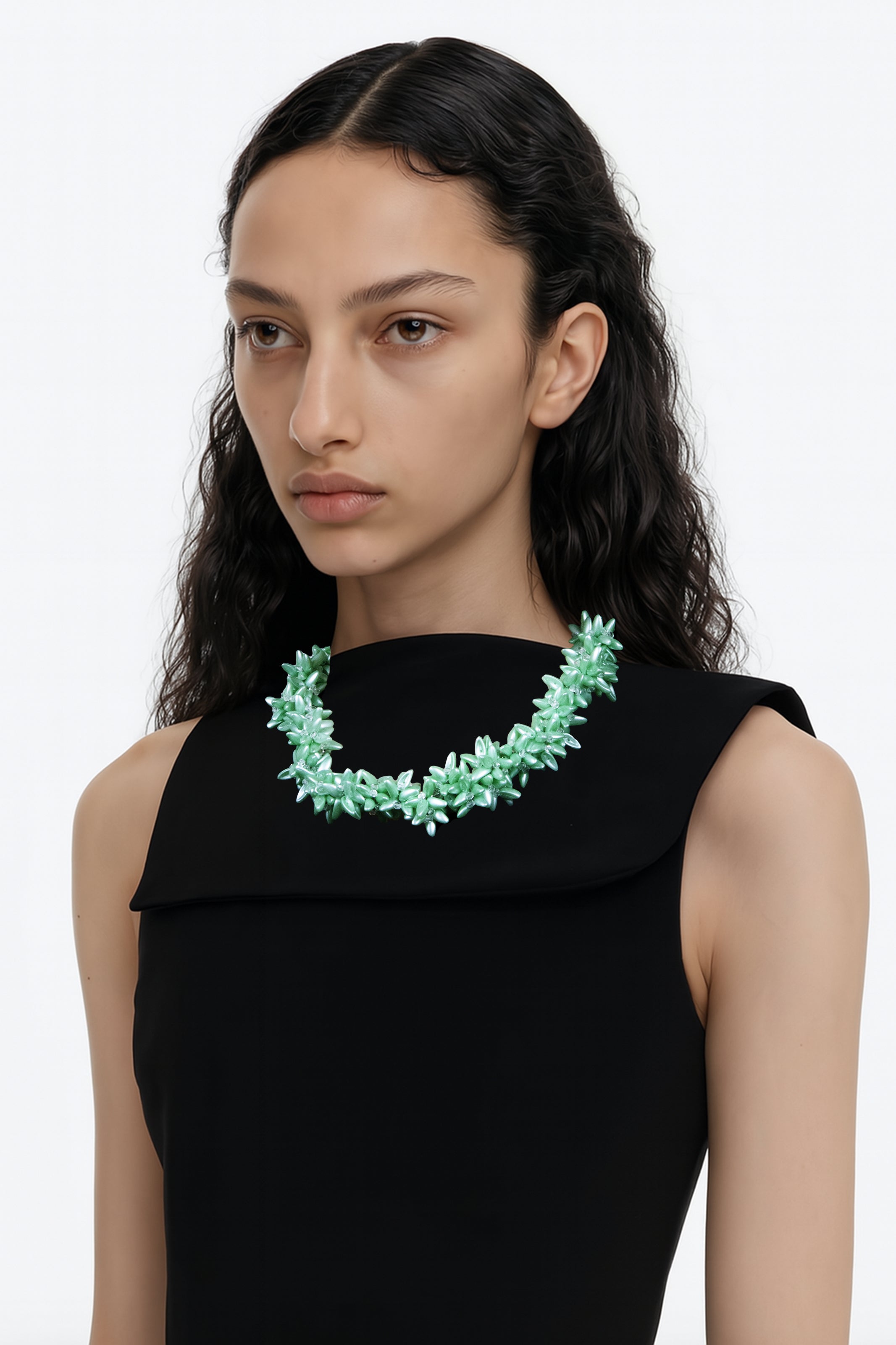 Model wearing a black dress with a green floral crystal beads necklace on a white background