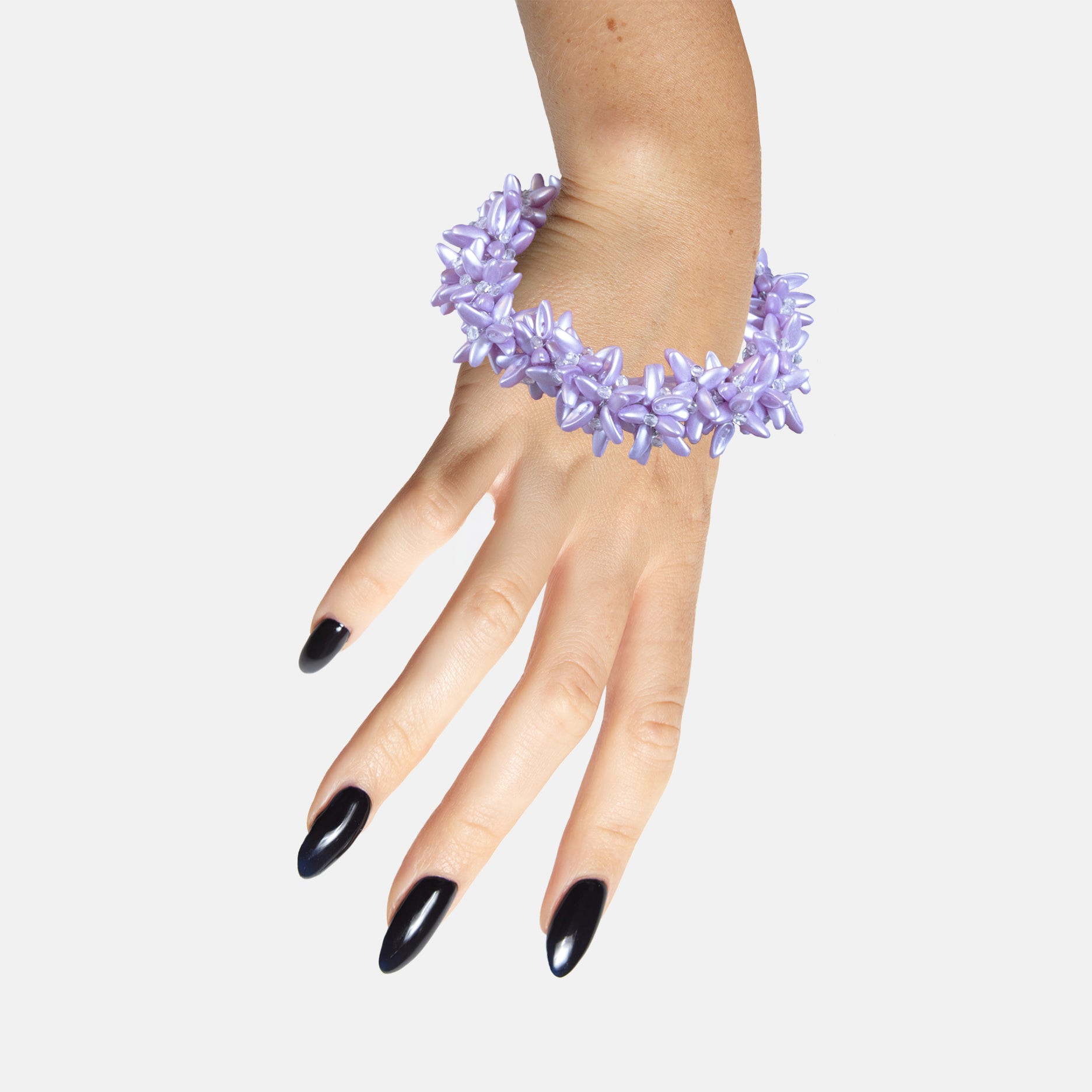 Hand wearing a purple floral statement beaded bracelet on a white background