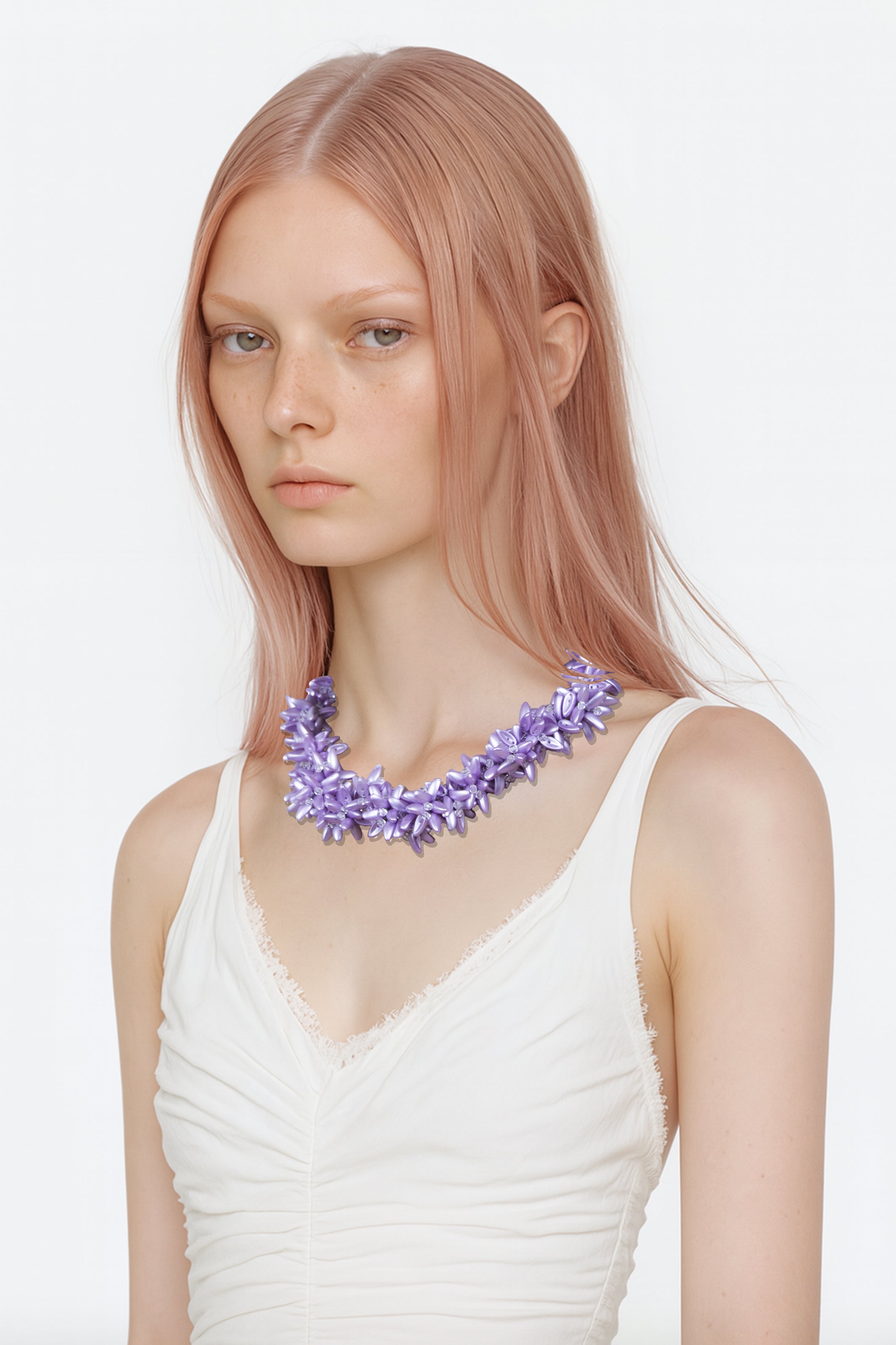 Model wearing a white top with a purple floral crystal beads necklace on a white background