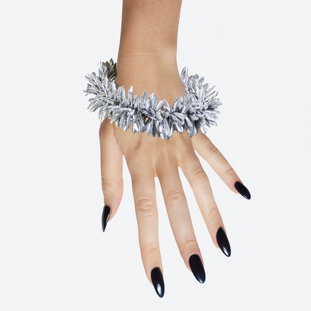 model hand wearing a multi beaded silver floral statement bracelet on a white background