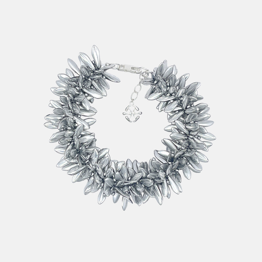 Silver statement bracelet with multi beaded silver flowers on a light gray background
