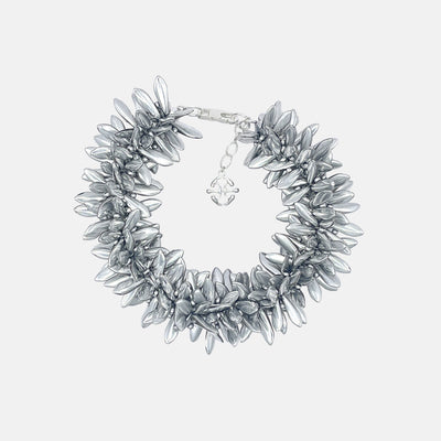 Silver statement bracelet with multi beaded silver flowers on a light gray background