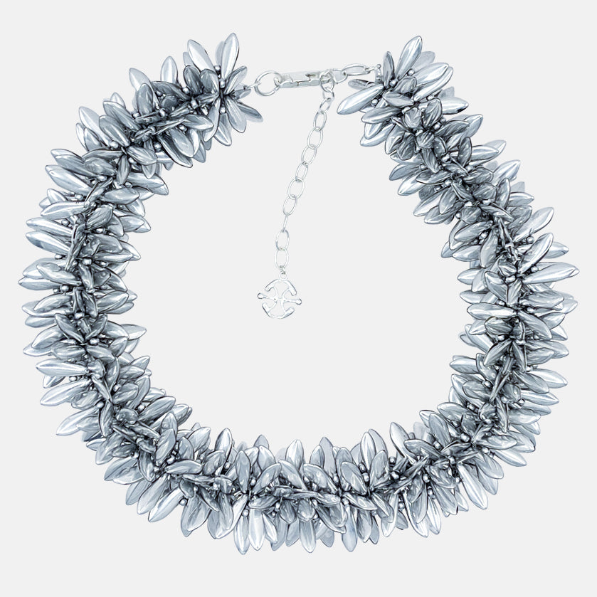 Silver statement necklace with multi beaded silver flowers on a light gray background