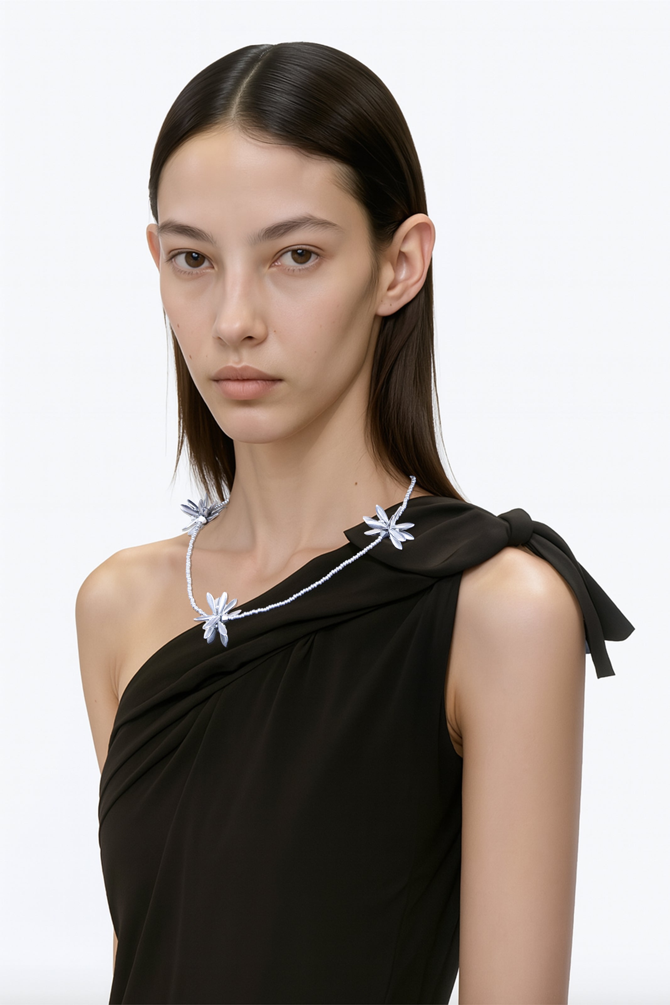 Model wearing a necklace with silver floral-shaped beaded choker on a plain background