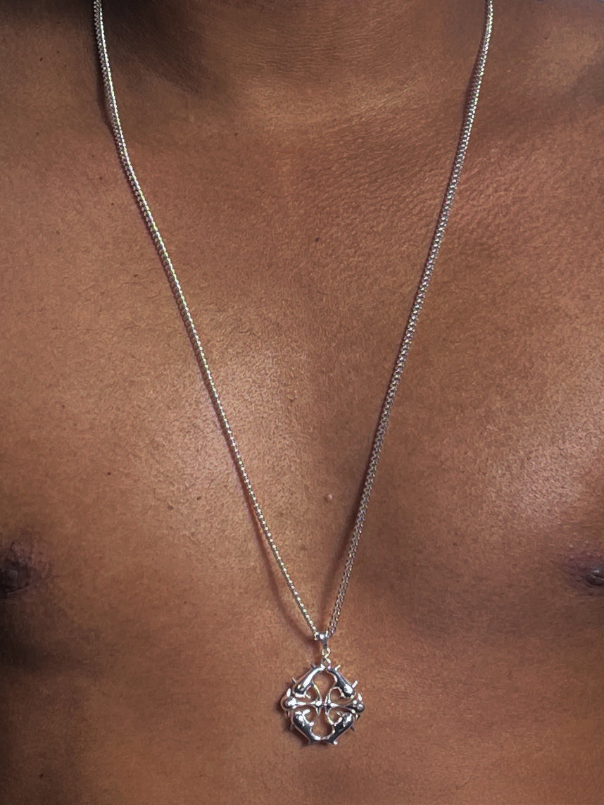 Silver logo necklace with spikes pendant on a person's neck