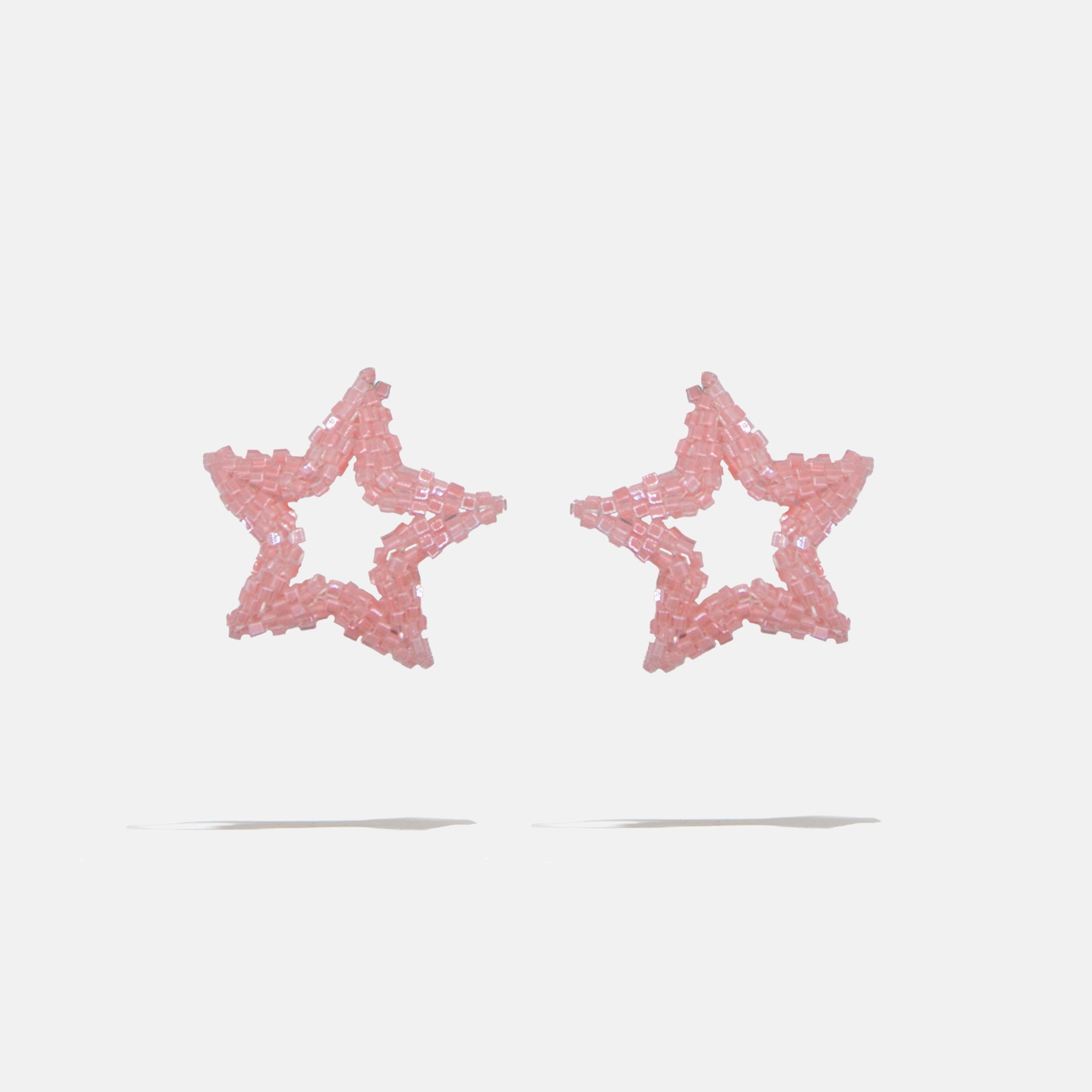 Star-shaped beaded earrings with pink glitter on a light gray background
