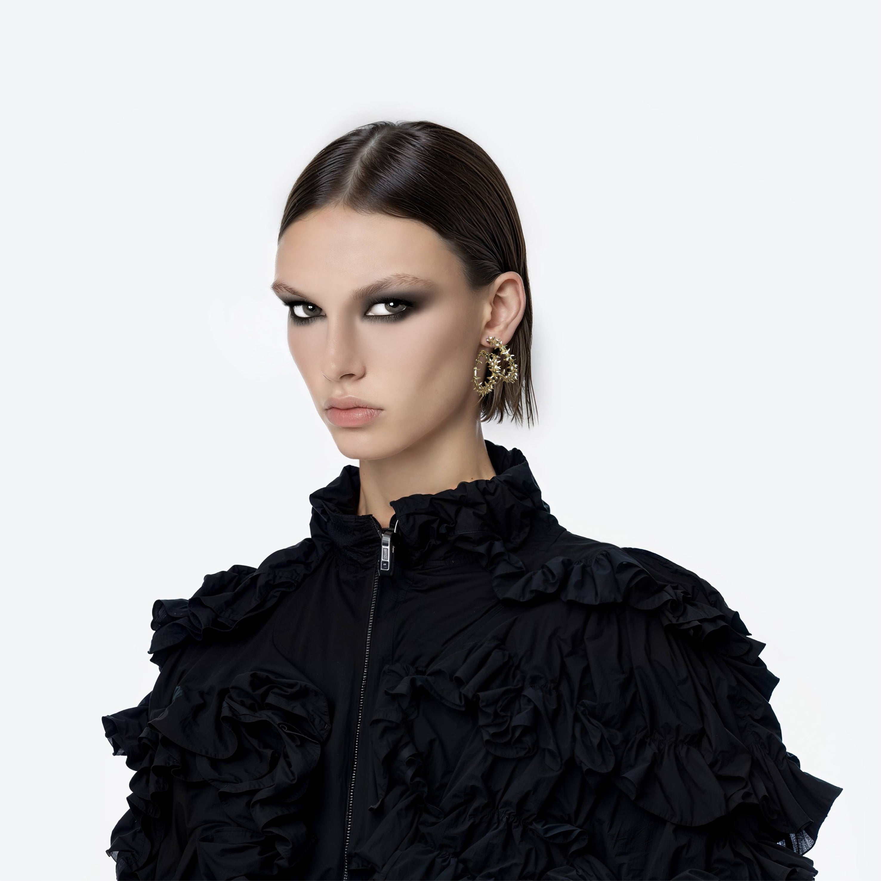 A brass gold spikes hoop fantasy earring worn by an AI model with  black ruffle  jacket and short dark hair view from 3/4
