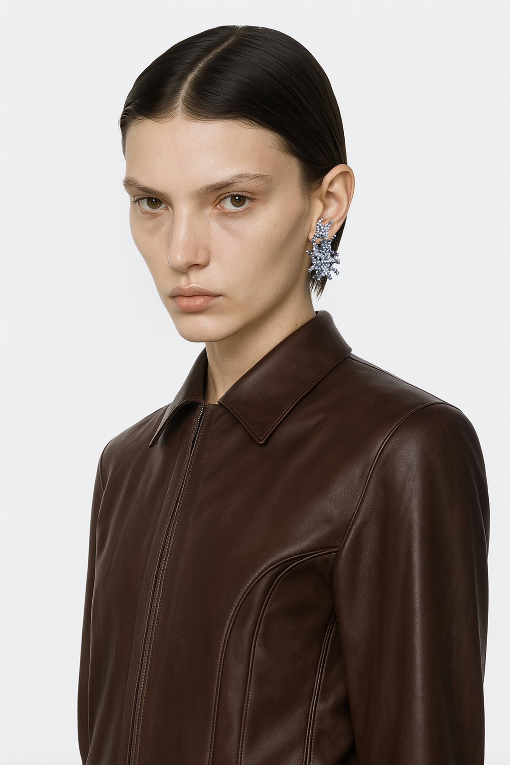 A brass silver handcrafted beads hoop stud fantasy earring worn by an AI model with leather brown tailored jacket and short dark hair view from 3/4