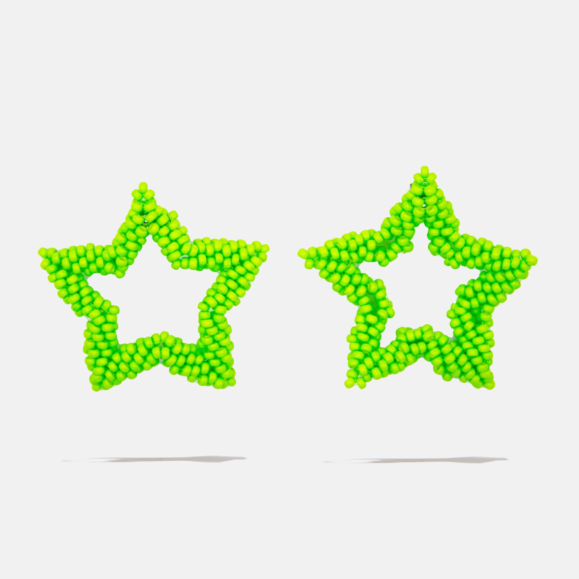 Two green star-shaped beaded earrings on a light gray background